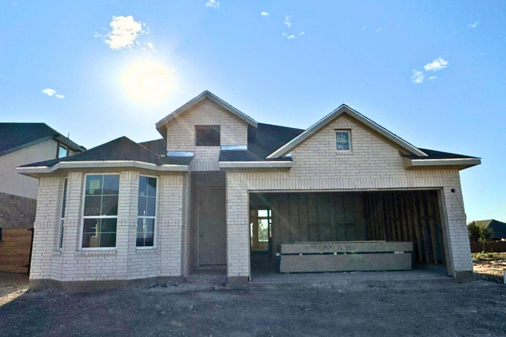 View of front facade with brick siding, a garage, and driveway