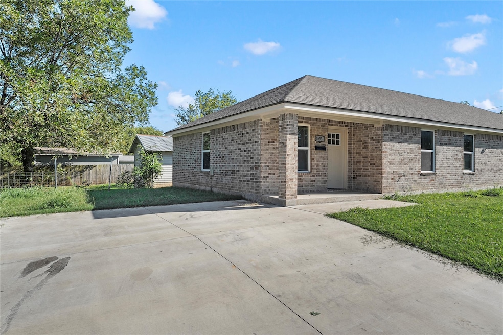 View of front of home featuring brick siding, roof with shingles, and a patio