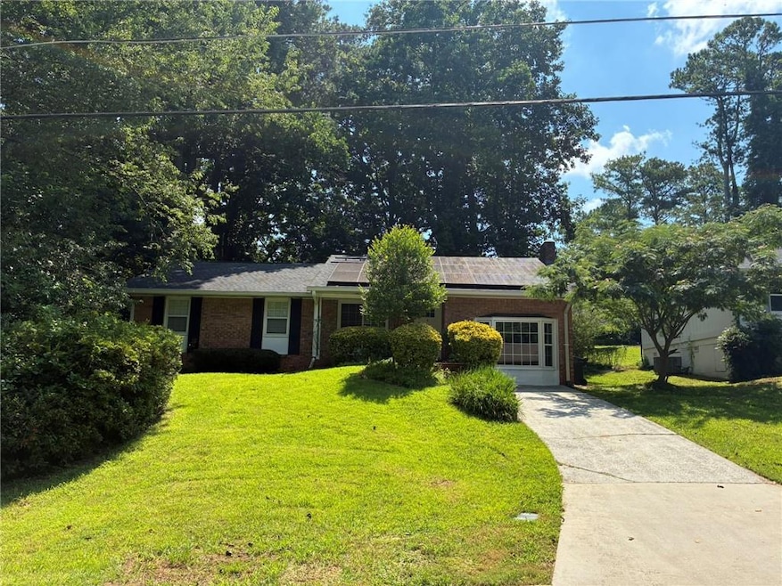 View of front facade with brick siding, a front lawn, solar panels, and concrete driveway