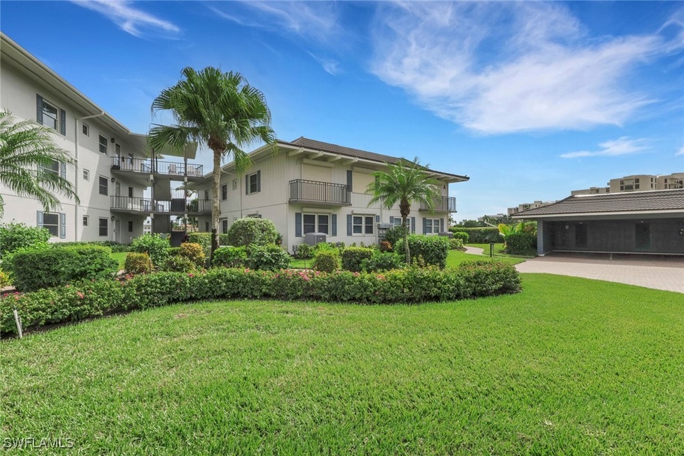 Rear view of property with a yard, stucco siding, and a balcony