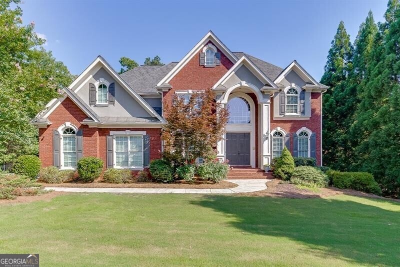 View of front of home featuring brick siding, a front yard, and stucco siding