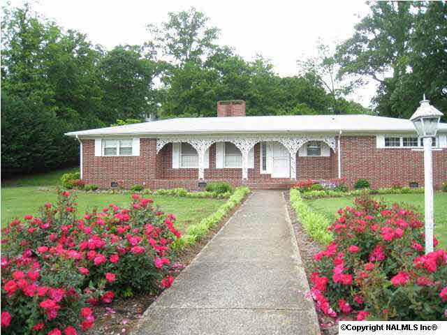 Front view with roses aligning the concrete sidewalk. Level Lot.