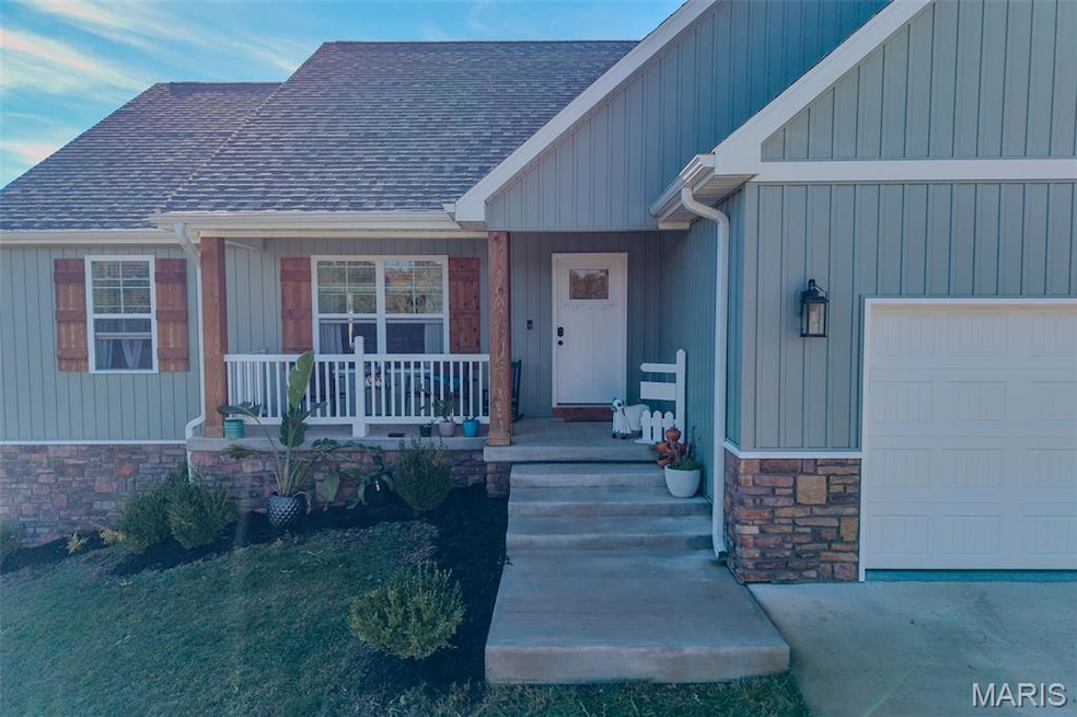 Property entrance featuring a garage, a shingled roof, stone siding, and covered porch