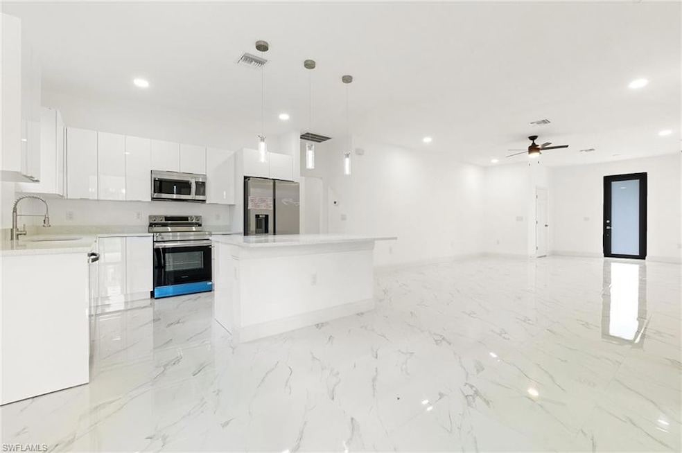 Kitchen with appliances with stainless steel finishes, a kitchen island, white cabinetry, recessed lighting, and pendant lighting