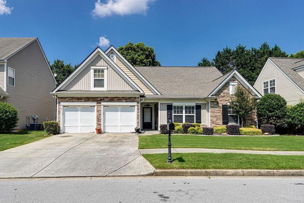 Craftsman-style house with board and batten siding, concrete driveway, a front lawn, stone siding, and an attached garage