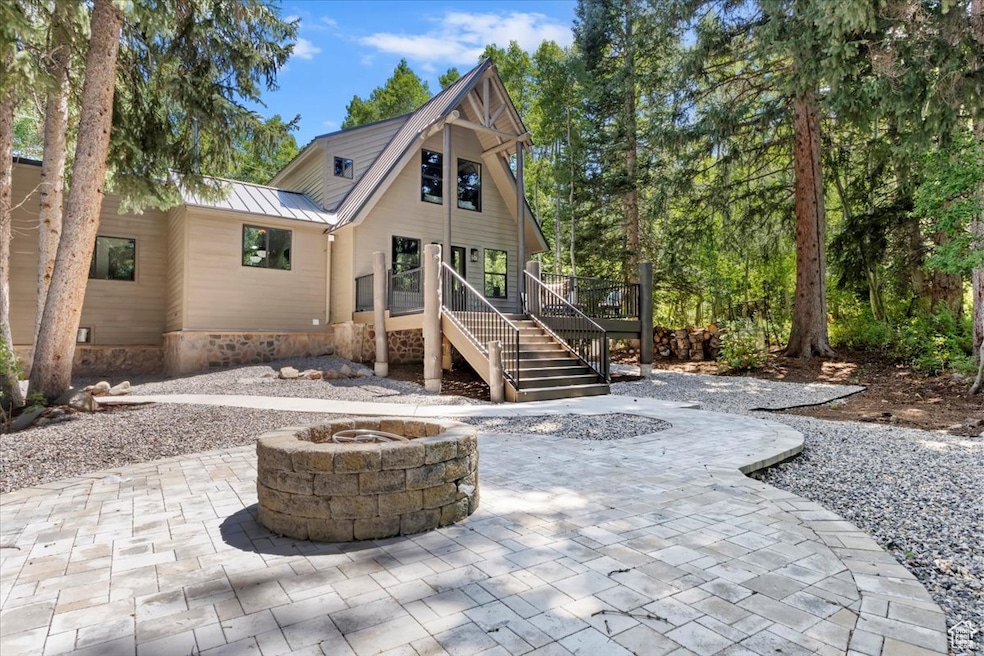 Rear view of property featuring an outdoor fire pit, stairs, a metal roof, a patio, and a standing seam roof