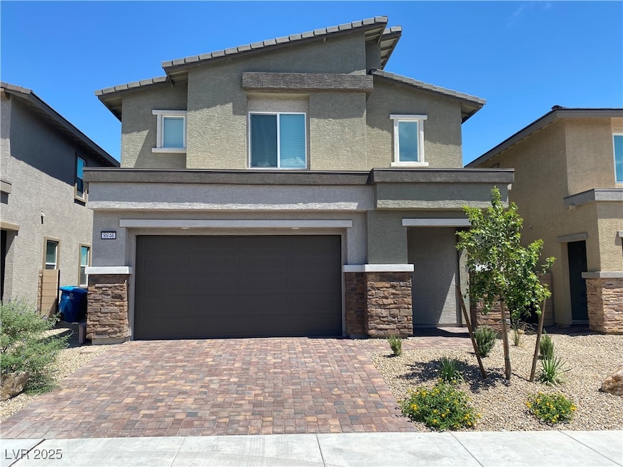 View of front of property featuring stone siding, stucco siding, decorative driveway, and an attached garage