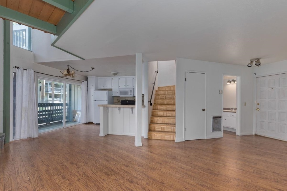 Unfurnished living room featuring wood finished floors, stairway, and heating unit