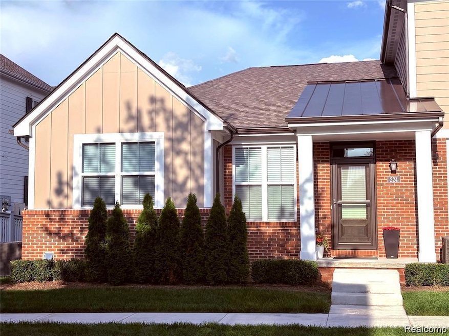 View of front of house featuring brick siding, board and batten siding, roof with shingles, and a standing seam roof