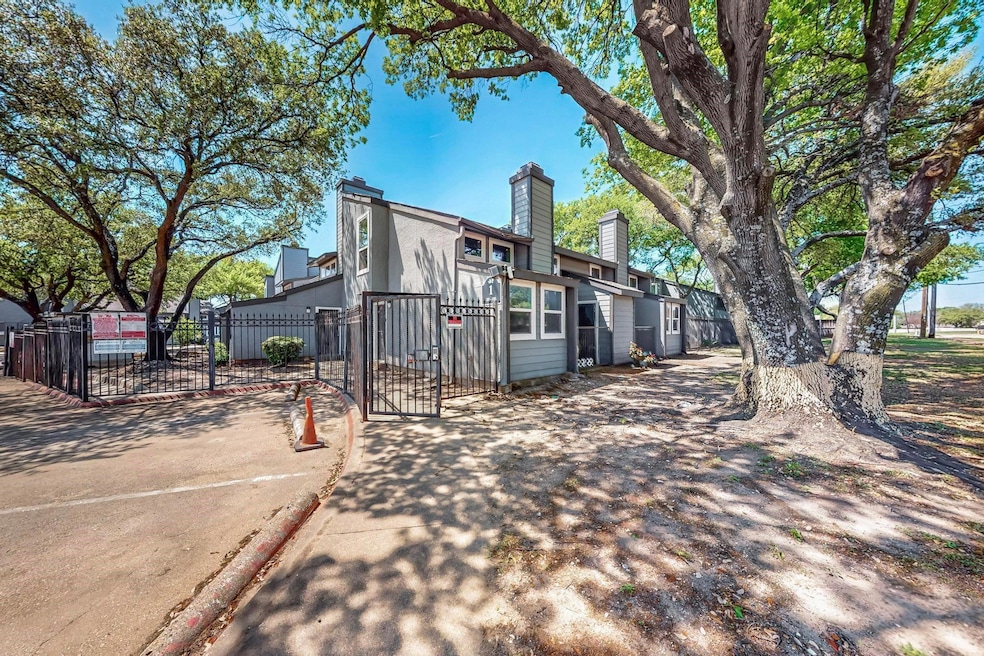 Rear view of house featuring fence, a gate, stucco