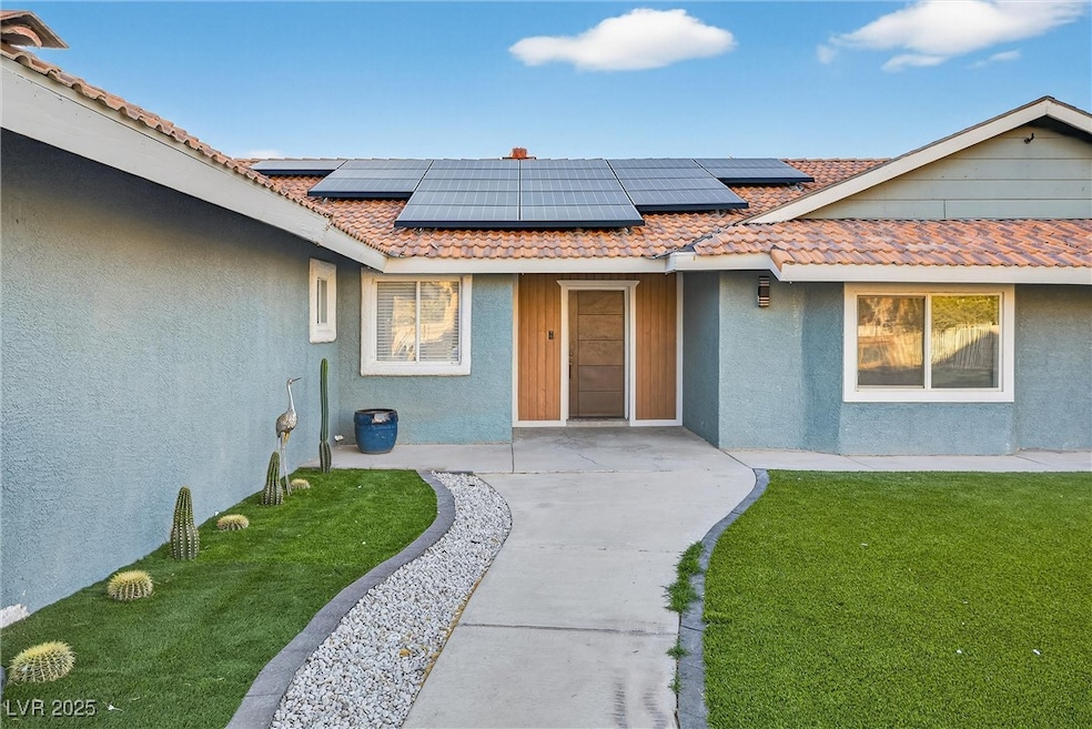 Entrance to property with stucco siding, a yard, and roof mounted solar panels