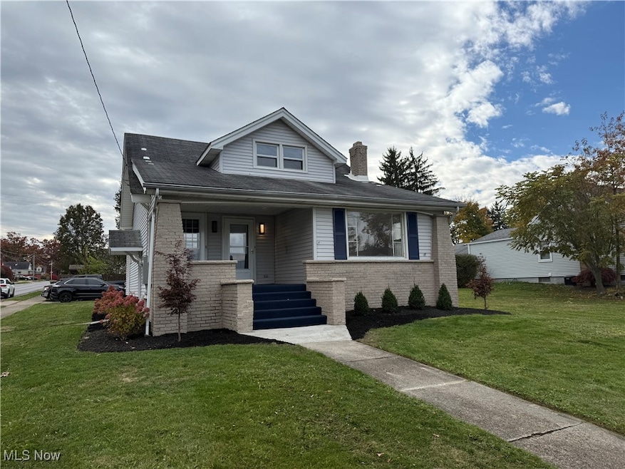 Bungalow-style house with a front yard, brick siding, a porch, and a chimney