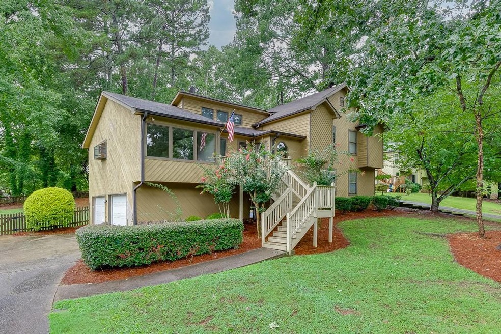 View of front of home featuring stairs, an attached garage, driveway, and view of wooded area