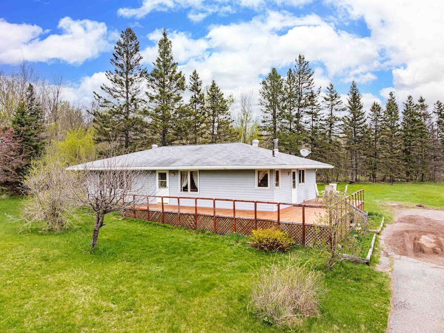 View of side of property with a yard and a wooden deck