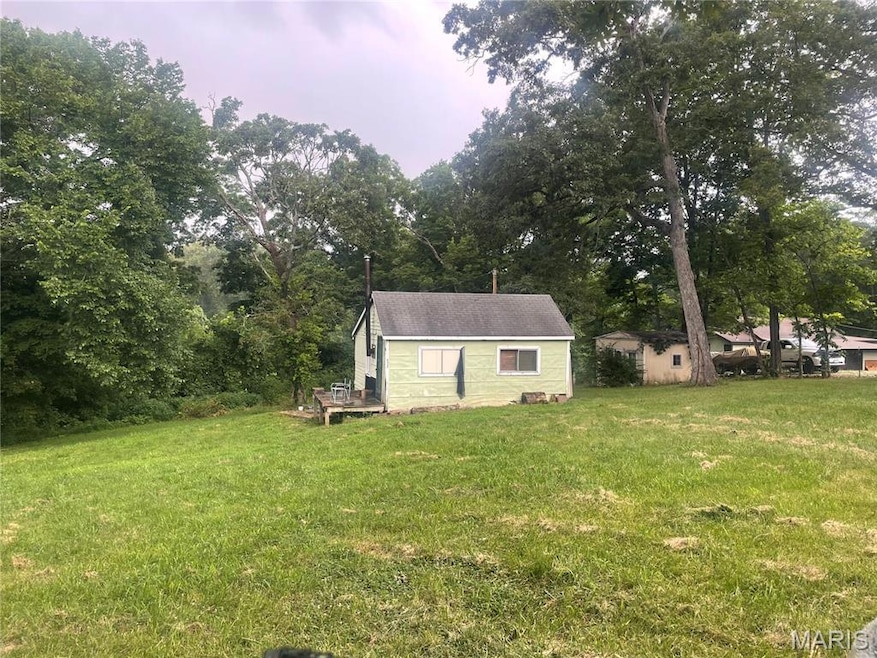 View of green lawn with a deck and an outdoor structure