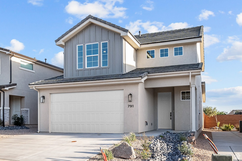 View of front facade featuring driveway, board and batten siding, an attached garage, and stucco siding