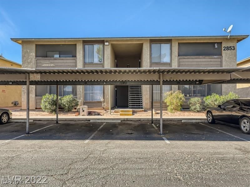 Rear view of property with covered parking and stucco siding