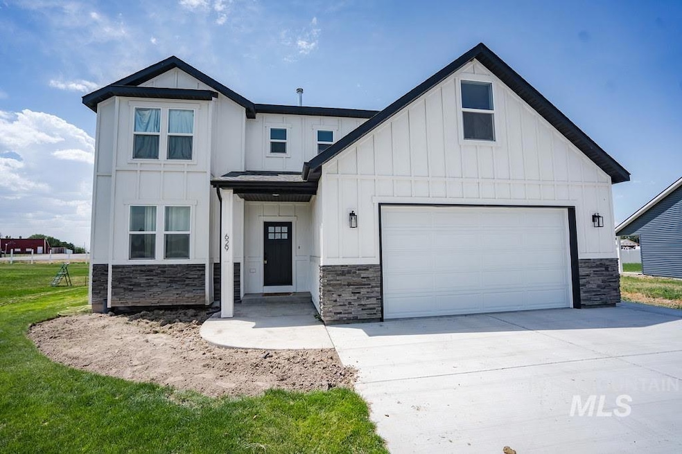 Modern farmhouse with stone siding, board and batten siding, driveway, and an attached garage