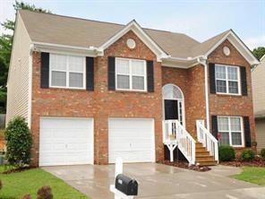 Raised ranch with driveway, brick siding, and a garage