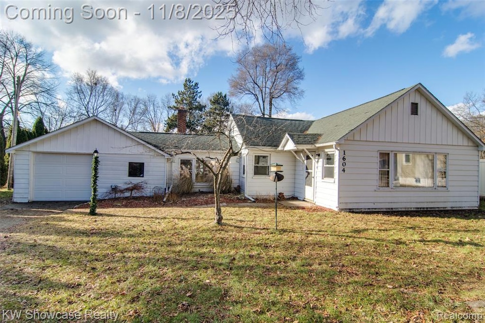 Ranch-style home with board and batten siding, a front yard, roof with shingles, a chimney, and an attached garage