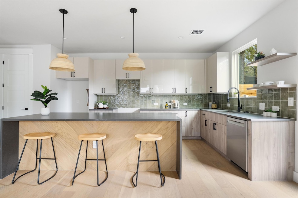 Kitchen featuring a breakfast bar, light wood finished floors, a center island, open shelves, and hanging light fixtures