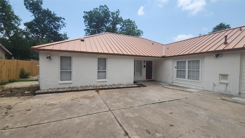 Rear view of property with a metal roof, brick si