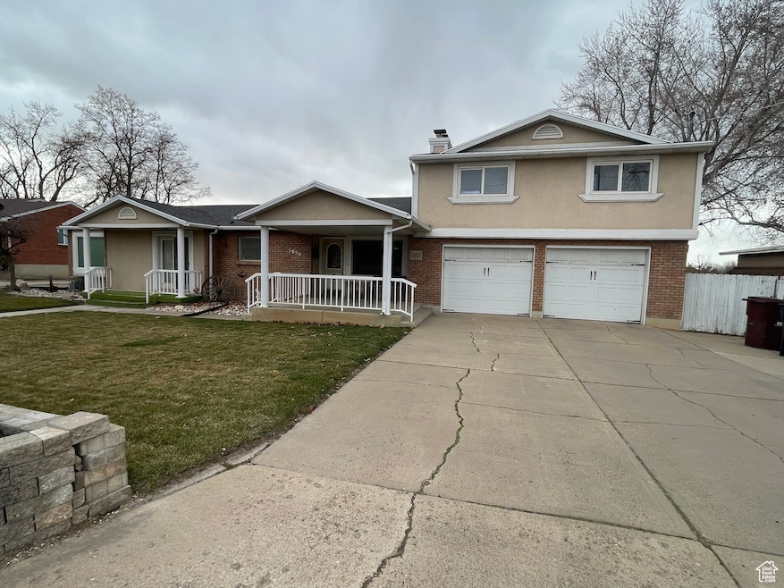 View of front facade with covered porch, a front yard, stucco siding, and brick siding