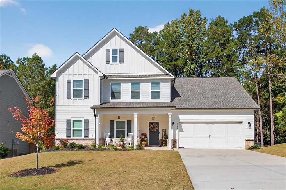 View of front of house with board and batten siding, a porch, driveway, and a front lawn