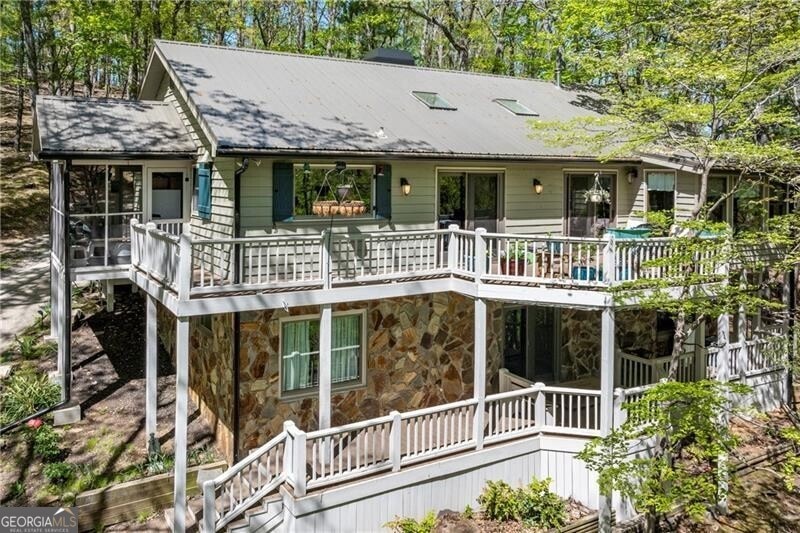 Back of property featuring stone siding, a wooden deck, and a chimney