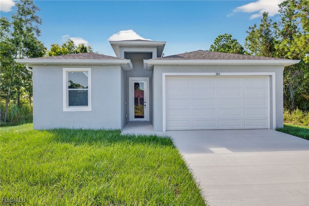 View of front of house with stucco siding, concrete driveway, an attached garage, and a front yard