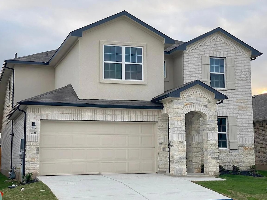 View of front of house featuring stone siding, driveway, stucco siding, and a shingled roof