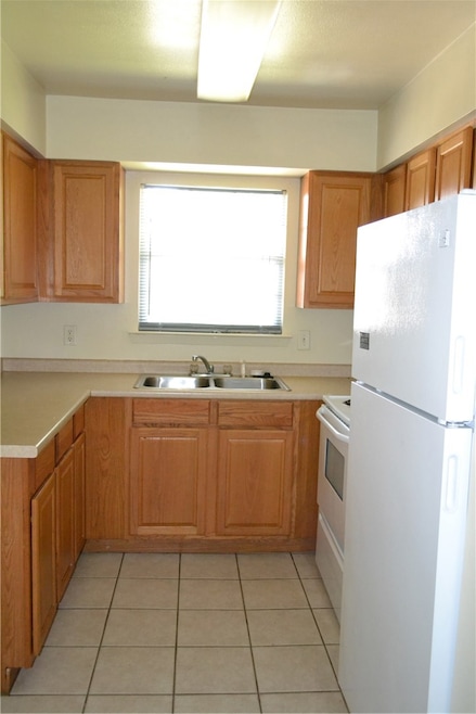 Kitchen featuring refrigerator, a sink, light tile