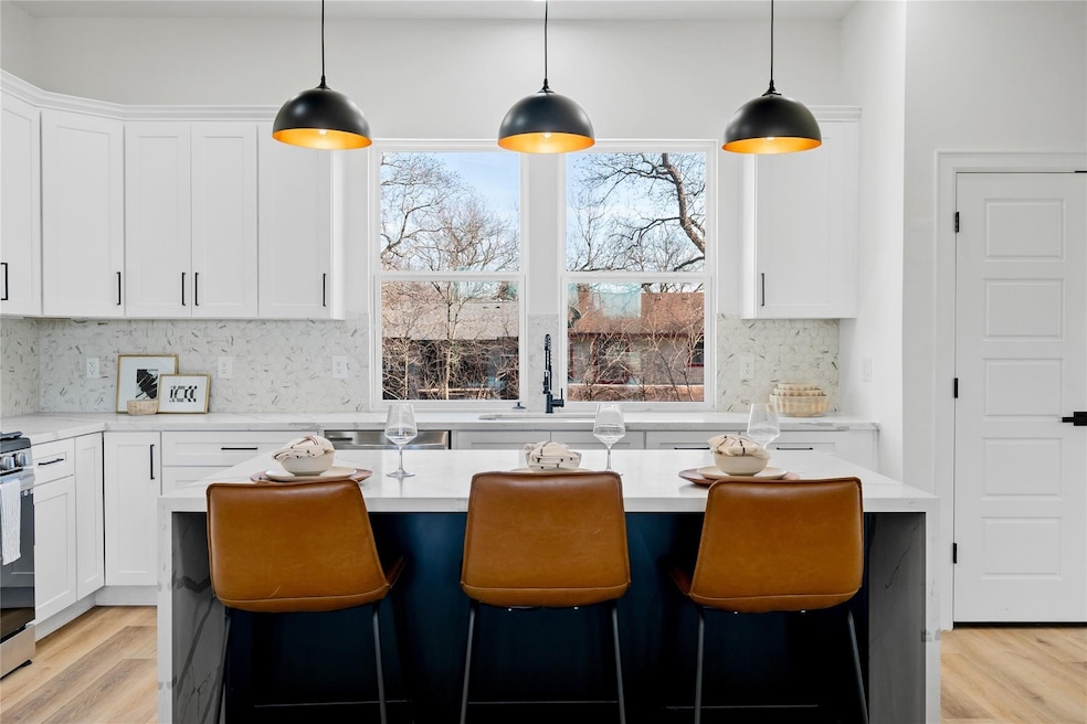 Striking contrast island with seating for three, matte black lighting, and oversized windows that bring in gorgeous natural light.