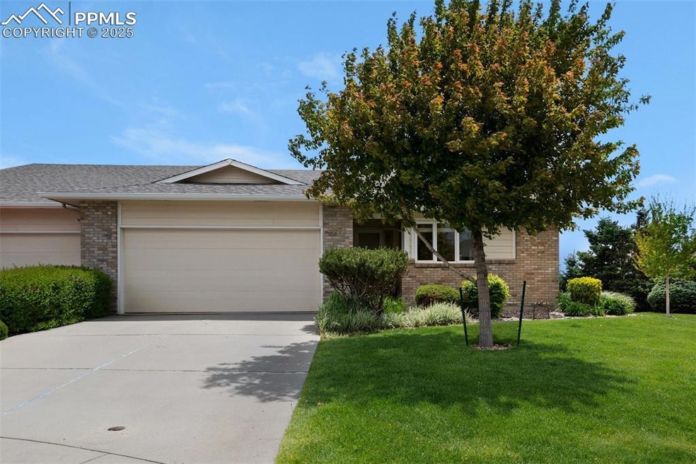 View of front of property with brick siding, an attached garage, a front lawn, driveway, and roof with shingles