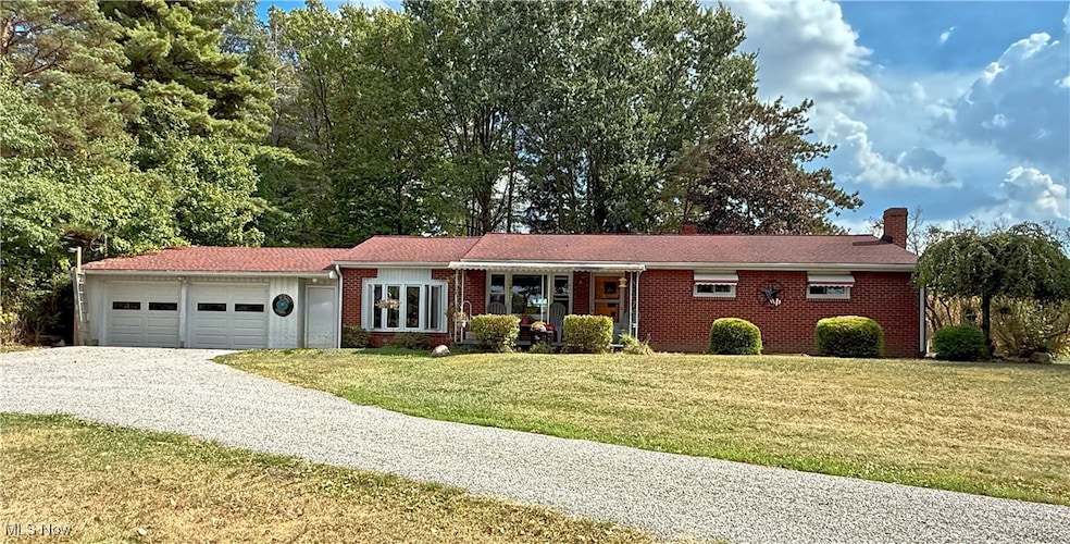 Ranch-style house with driveway, a front yard, an attached garage, brick siding, and a chimney
