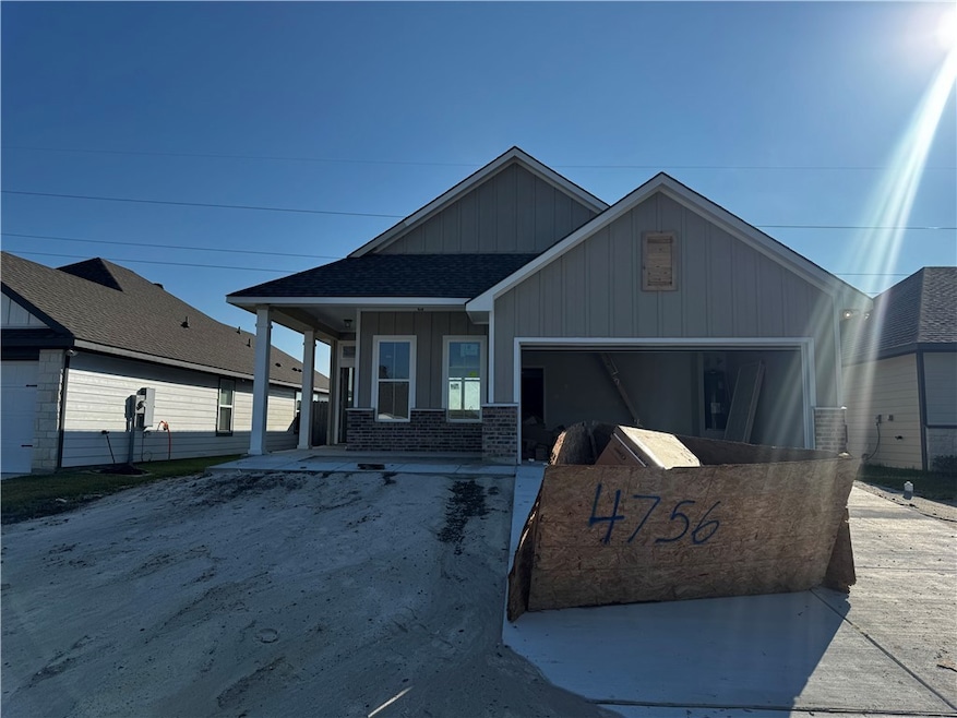 View of front facade with board and batten siding, concrete driveway, brick siding, and a porch