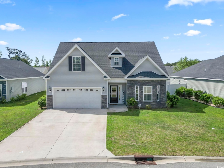 Traditional home with a garage, a front yard, ston