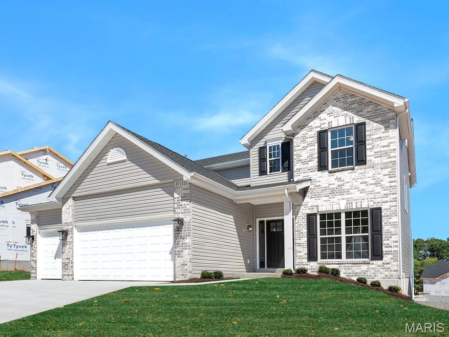 Traditional-style home featuring a front lawn, driveway, brick siding, and an attached garage