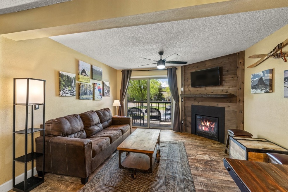 Living room with a ceiling fan, a large fireplace,