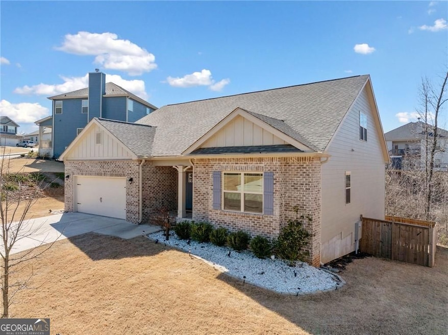 View of front of property featuring a garage, concrete driveway, brick siding, and board and batten siding