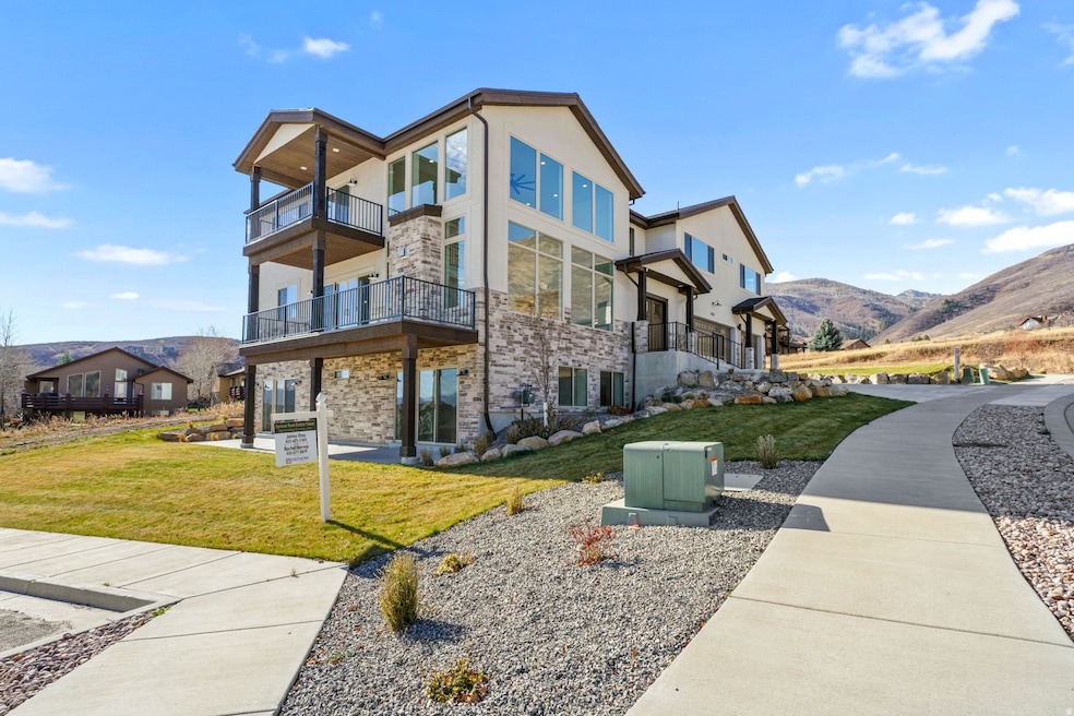 View of property exterior featuring a balcony, a mountain view, and a lawn