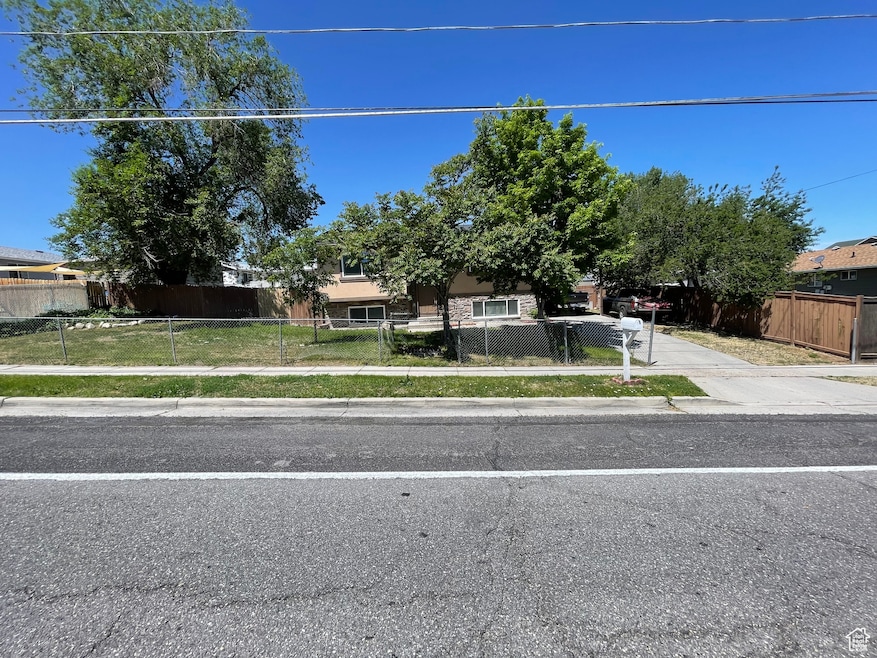 View of property hidden behind natural elements featuring a fenced front yard and concrete driveway