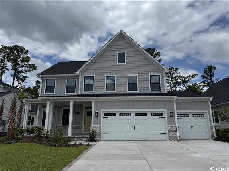 View of front facade featuring board and batten siding, a porch, driveway, and a garage