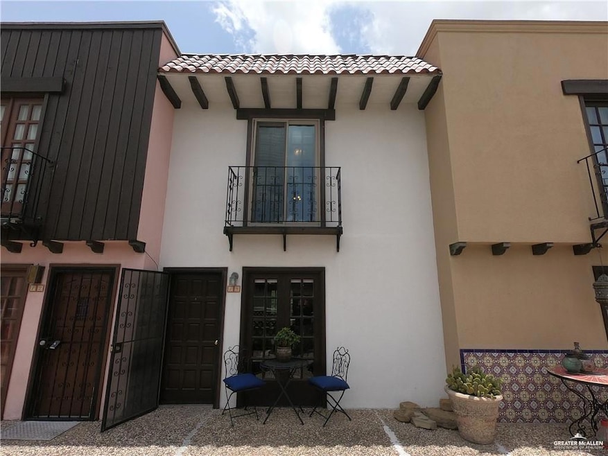 Rear view of property featuring stucco siding, a tiled roof, and a balcony