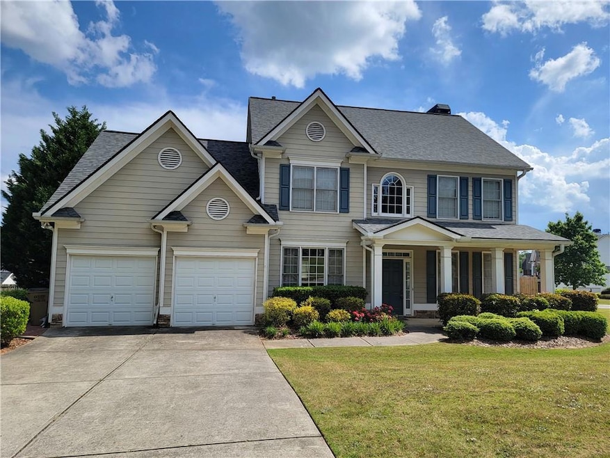 View of front facade featuring a garage, concrete driveway, and a front yard