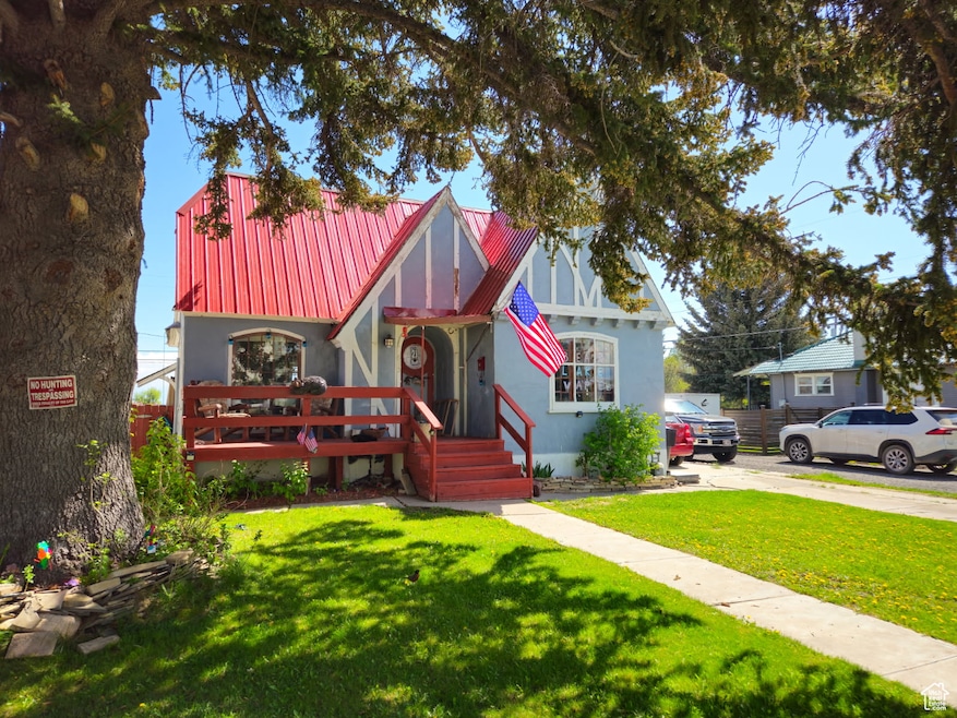 Tudor home featuring metal roof, a front yard, and concrete driveway