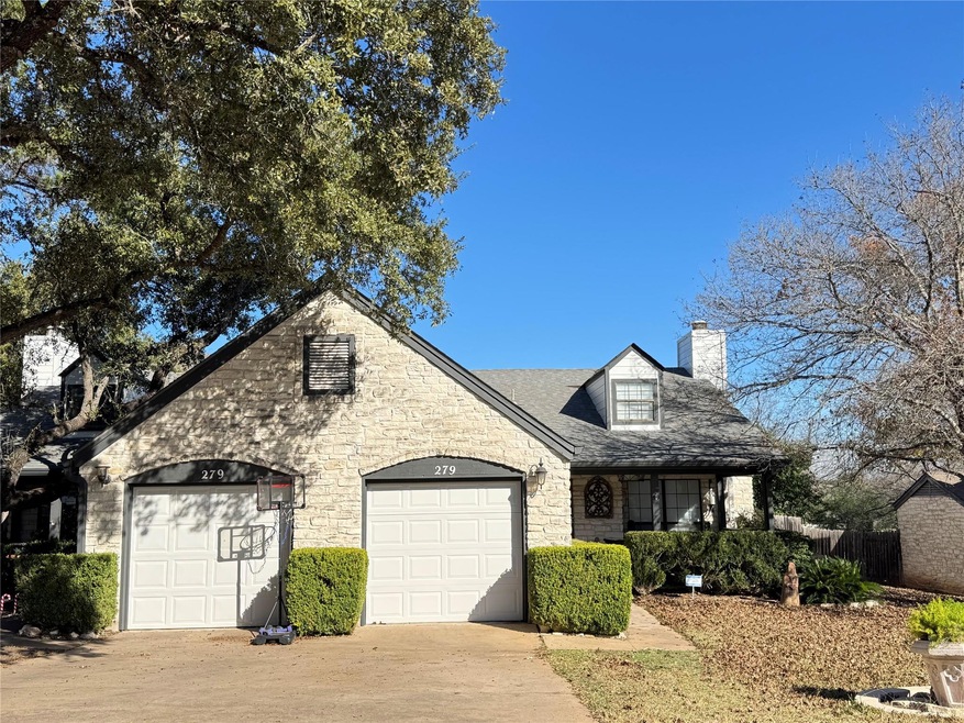 View of front of house with a chimney, concrete driveway, an attached garage, and stone siding