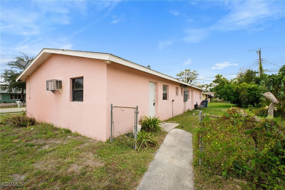 View of property exterior featuring stucco siding, a yard, a wall unit AC, and a gate