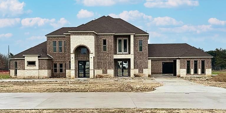 View of front facade with driveway and brick sidin