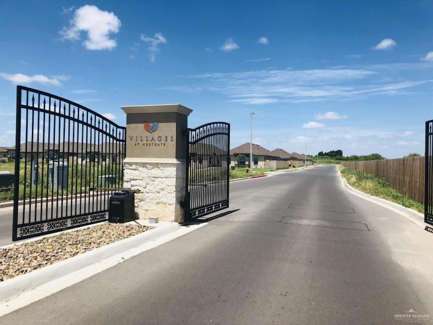 View of asphalt road featuring curbs, a gate, and a gated entry